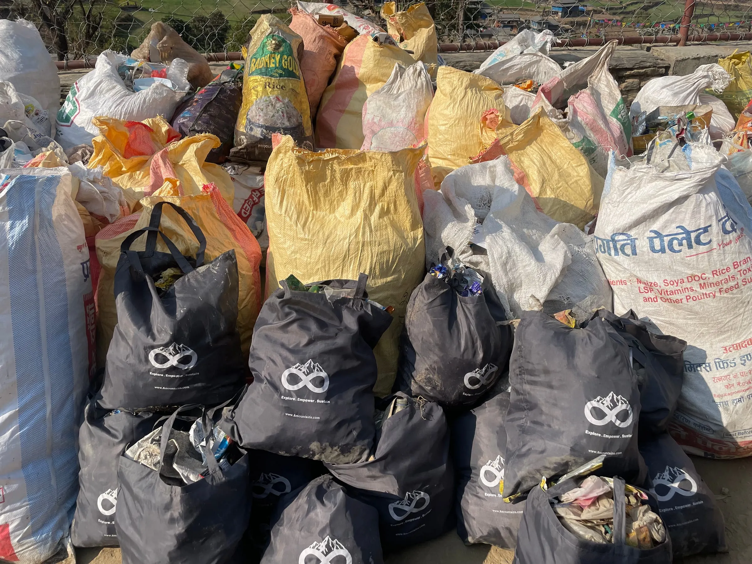 Branded 8Mountains bags and yellow woven sacks stacked in a heap after the collection.