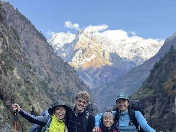 Natálie and her group with their guide on the trail, snow ridges rising across the valley behind them.