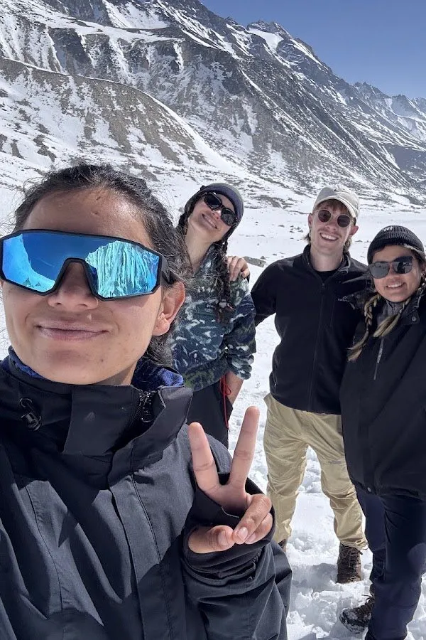 A close group photograph in the snow, the guide in sunglasses in the foreground and three travellers behind.