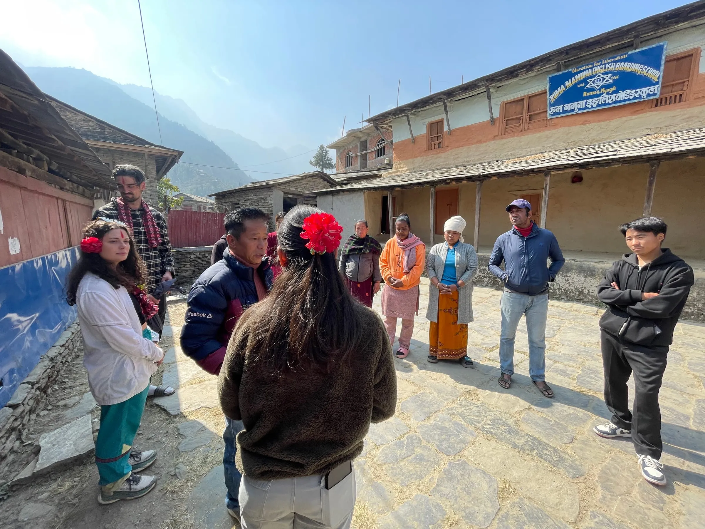 Villagers gathered in the open ground at the centre of Ruma, slate-roofed houses around them.