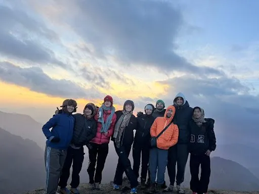 The whole trekking group lined up together at golden hour on the Dura Lekh.